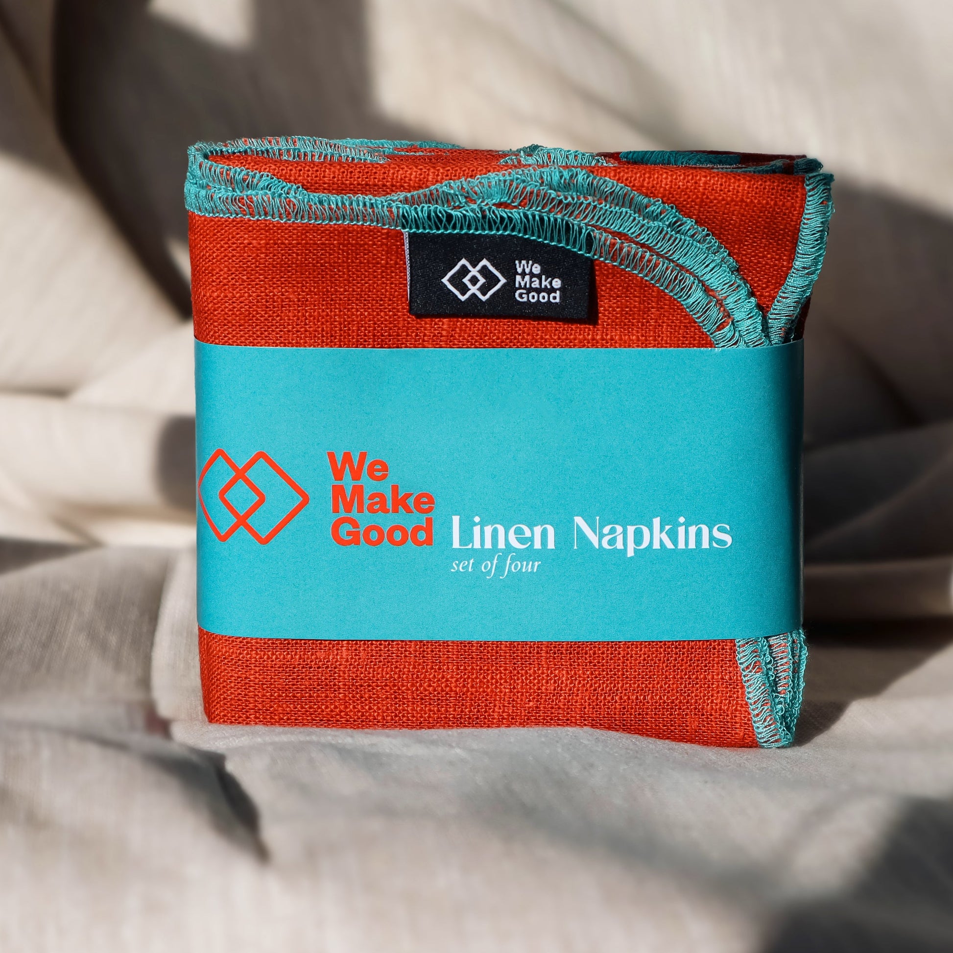 Pack of We Make Good linen napkins on a textured surface