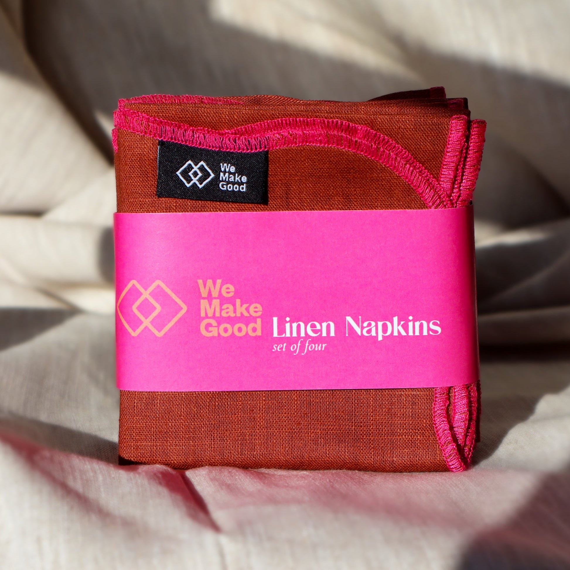 Pack of linen napkins with pink label on a textured fabric background